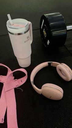 headphones, coffee cup and pink scarf laid out on the ground next to each other