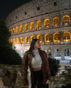 a woman standing in front of the colossion at night with her hand on her hip