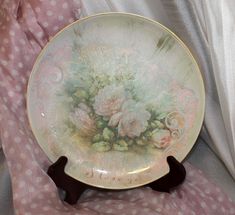 a plate with flowers painted on it is sitting on a pink polka dot cloth covered chair