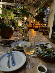 a wooden table topped with plates and glasses of wine