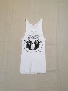 "1970s band tanktop shirt Hanes, cotton, white ribbed The Manhattan Transfer black print Atlantic Records symbol at lower right of image front/back image good vintage condition, light wear light stains, light cracking label size M, see below measures, lying flat, chest-12\" unstretched to 19\" stretched length-26\"" Fitted Sleeveless Cotton T-shirt, Fitted Sleeveless Graphic Print T-shirt, Fitted Cotton Vest For Streetwear, Fitted Cotton Crew Neck Vest, Fitted White Muscle Tee For Summer, White Fitted Muscle Tee For Summer, Fitted Cotton Muscle Tee With Graphic Print, Spring Fitted Graphic Print Muscle Tee, Vintage Tank T-shirt For Summer