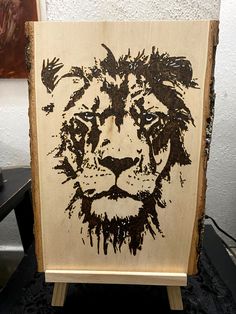 a painting of a lion is shown on a wooden easel in front of a white wall