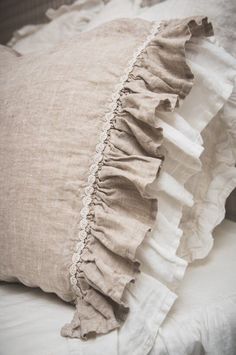 a close up of a pillow on a bed with ruffles and linen material