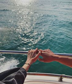 two people holding hands while riding on a boat