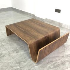 a wooden coffee table sitting on top of a marble floor next to a white wall