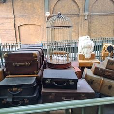 many suitcases are stacked on top of each other in front of a bird cage