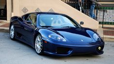 a blue sports car parked in front of a building with stairs on the side walk