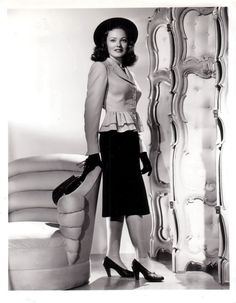 black and white photograph of woman in front of mirror with handbag on her hip