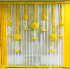 yellow and white decorations hanging from the side of a window with sheer drapes on it