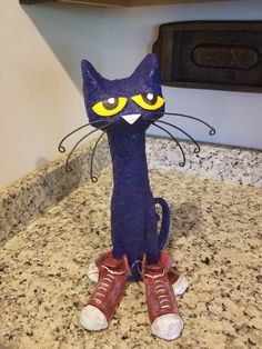 a blue cat figurine with yellow eyes sitting on top of a granite counter