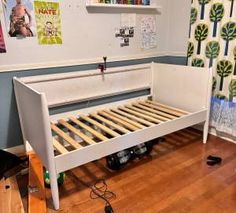 a white bed frame sitting on top of a hard wood floor next to a wall