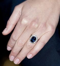 a close up of a person's hand with a blue ring on their finger