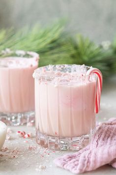 two glasses filled with pink liquid and candy canes