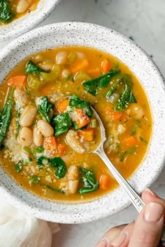 two bowls of soup with beans, spinach and carrots