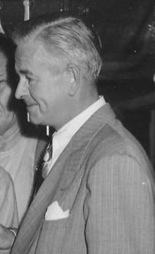 black and white photograph of two men in suits talking to each other at an event