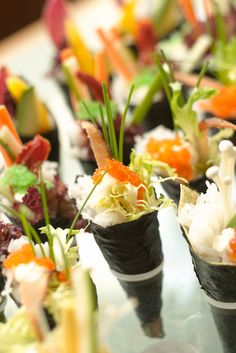 several sushi rolls are arranged on a glass table, with garnishes