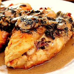 two pieces of chicken covered in mushrooms on a plate