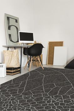 a black and white area rug in an office with a chair, computer desk, and art on the wall