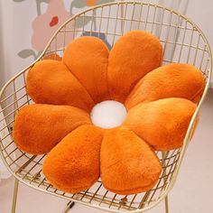 an orange flower shaped pillow sitting on top of a chair