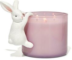 a white rabbit figurine sitting next to a pink candle