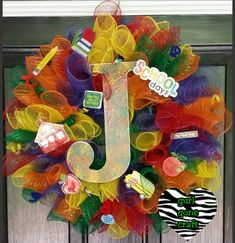 a colorful mesh wreath with the letter j on it's front door, decorated with various items