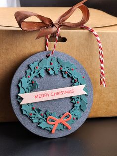 a christmas ornament hanging from a box with a ribbon and bow on it