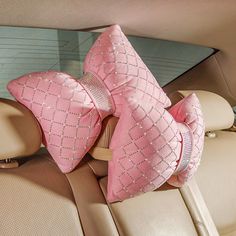 two pink pillows sitting on the back seat of a car