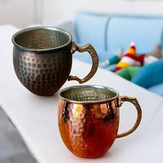 two metal cups sitting on top of a white table