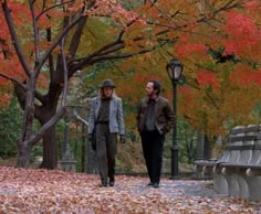 two people walking down a street in the fall