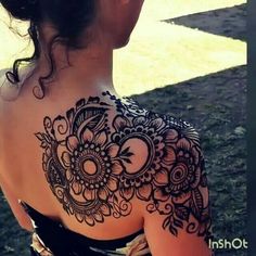 the back of a woman's shoulder with henna tattoos