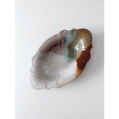 a white and brown shell shaped dish sitting on top of a table next to a wall