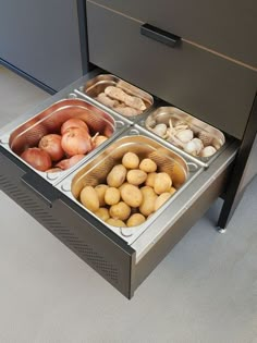 four trays of food sitting on top of a metal counter next to two drawers