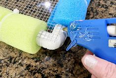 a hand holding a blue and white plastic blow dryer next to two sponges