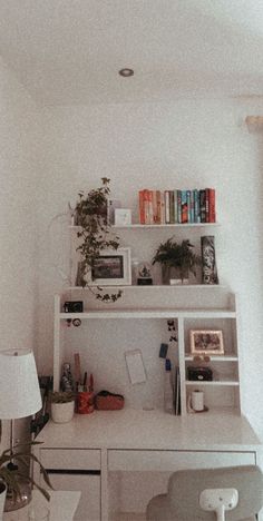 a white desk and chair in a room with books on the shelves above it, next to a lamp