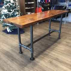 a wooden table sitting on top of a hard wood floor next to a christmas tree