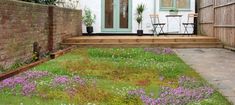 a small garden with flowers and grass in front of a house