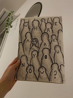 a hand holding up a drawing of people with words written on the front and back