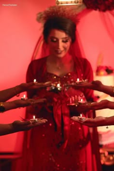 a woman in a red dress is holding out her hands with candles on each hand