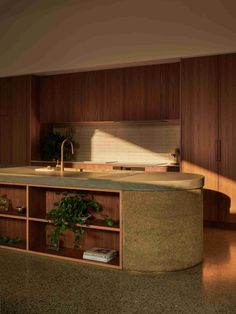 a kitchen with an island counter top and wooden cabinetry in the middle, surrounded by greenery