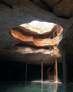 an indoor swimming pool with stairs leading up to the water's edge and large rocks on either side