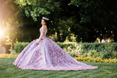 a woman in a purple dress and tiara standing on the grass with trees in the background