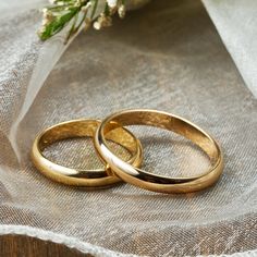 two gold wedding rings sitting on top of a table