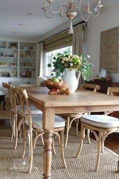 a dining room table with chairs and a vase on it