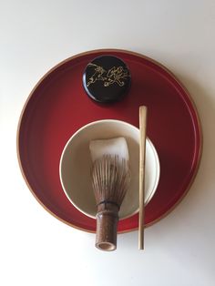 a red plate with a brush and bowl on it