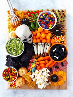 a wooden platter filled with halloween treats and candy sticks on top of a table