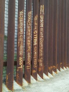 a row of rusted metal poles with writing on them