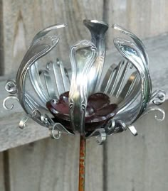 a metal vase sitting on top of a wooden table next to a fence covered in water droplets