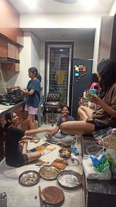 several people are sitting on the kitchen counter eating food and having fun with each other