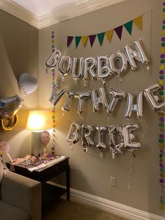 balloons and streamers are hanging on the wall above a couch in a living room