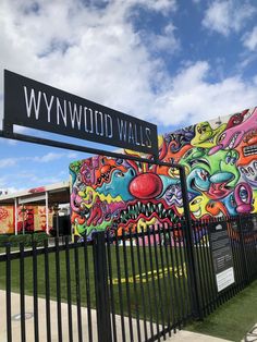 a street sign in front of a wall with graffiti on it and the words wynwood walls painted on it